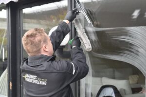 Professional cleaner washing a large glass window during a spring window cleaning service in Boise